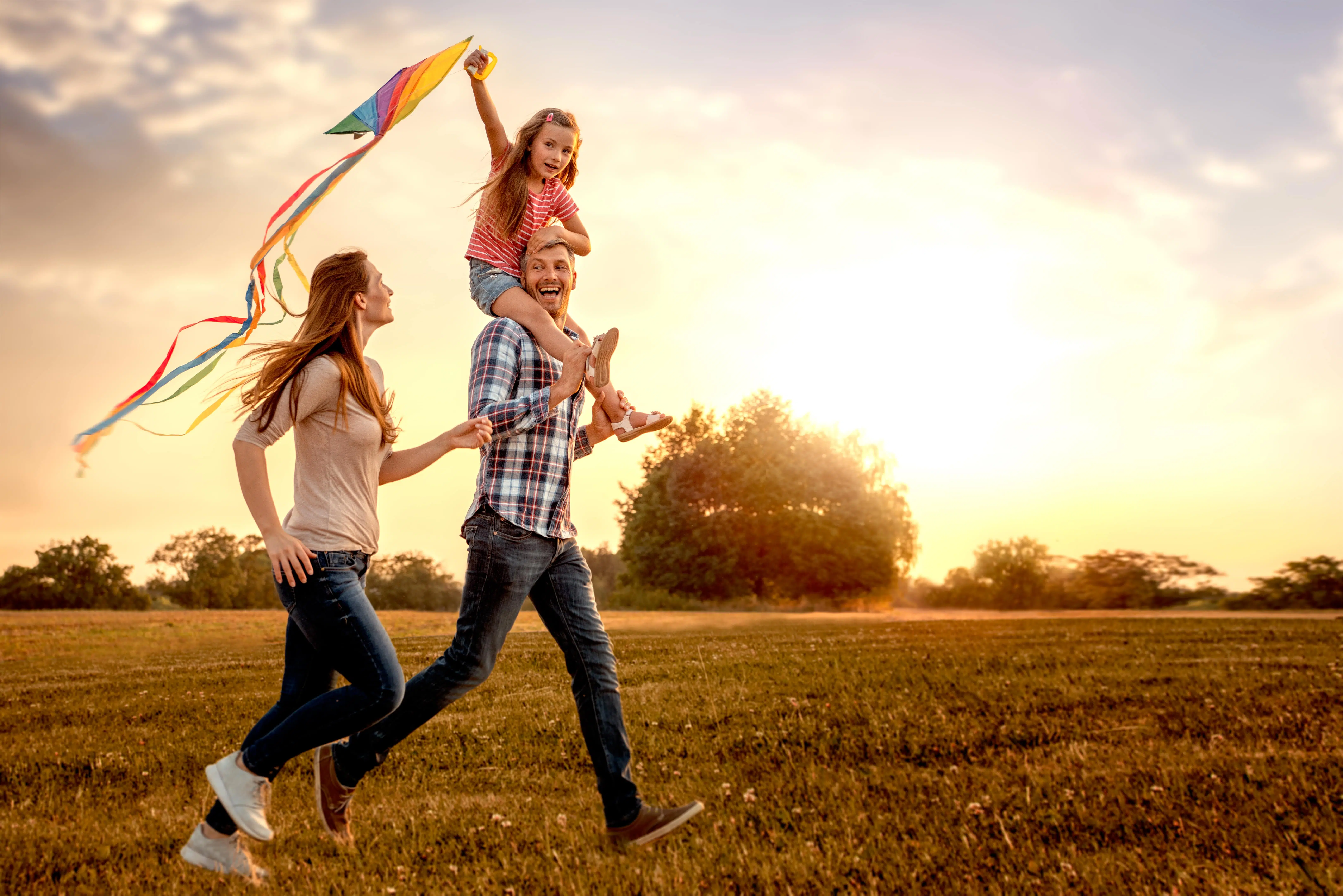 Happy Family Running Through A Field With A Kite To Represent Reflecting As A Fostering Agency
