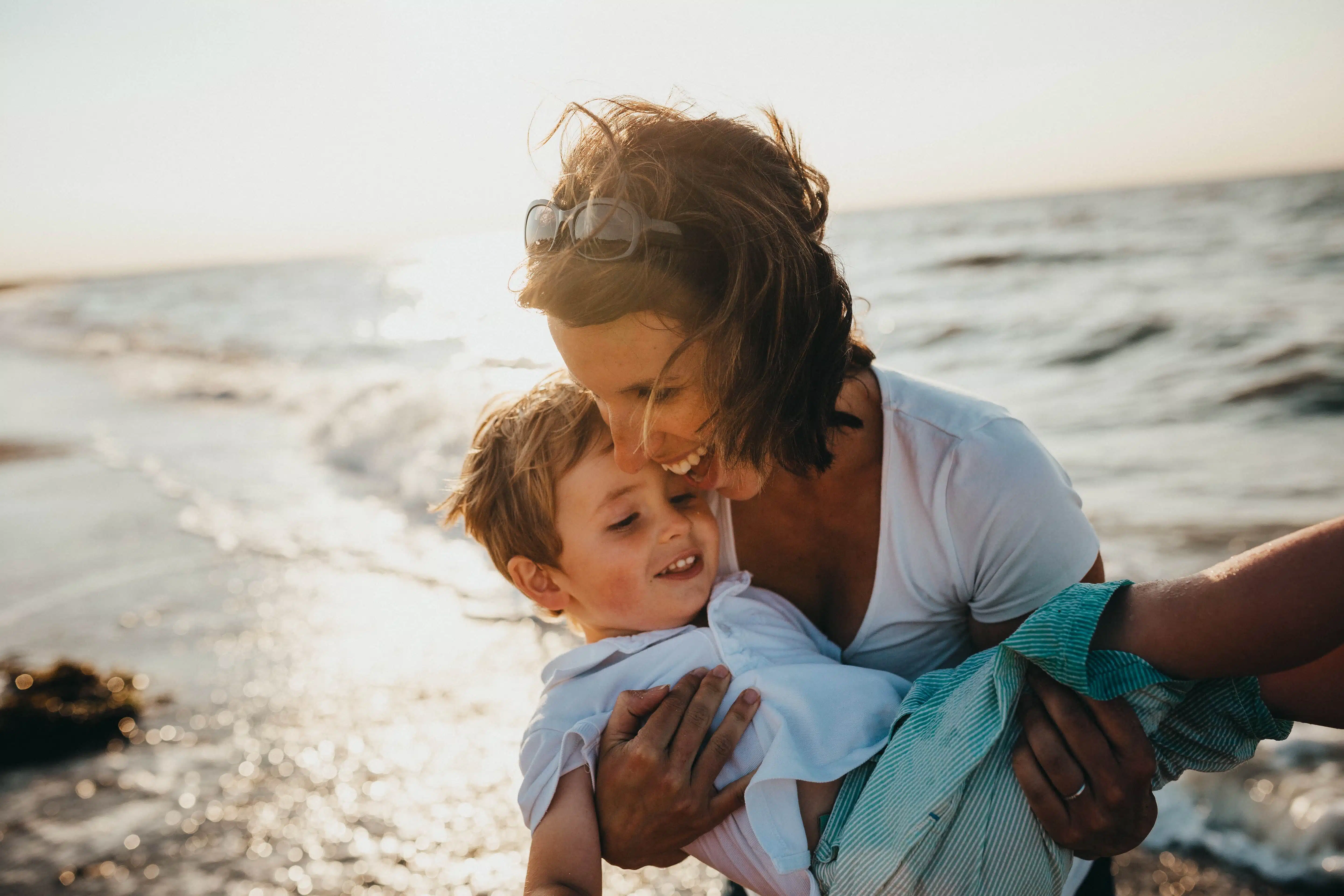 A woman with a child at the beach, laughing, playing in the sea.